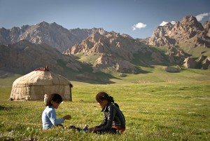 BGD57H Kyrgyz Children playing on the grass, Irkestan Pass, Kyrgyzstan