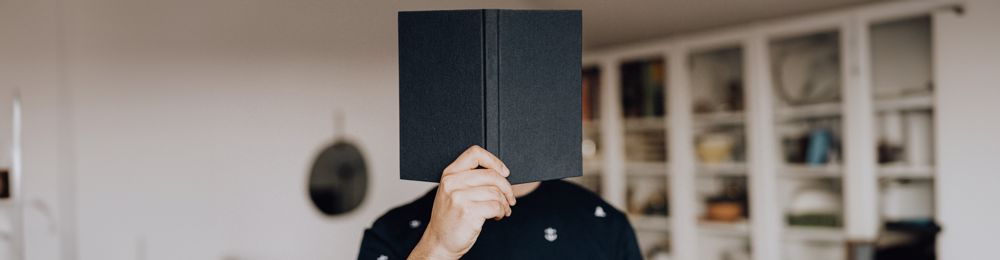 man holding a book infront of his face