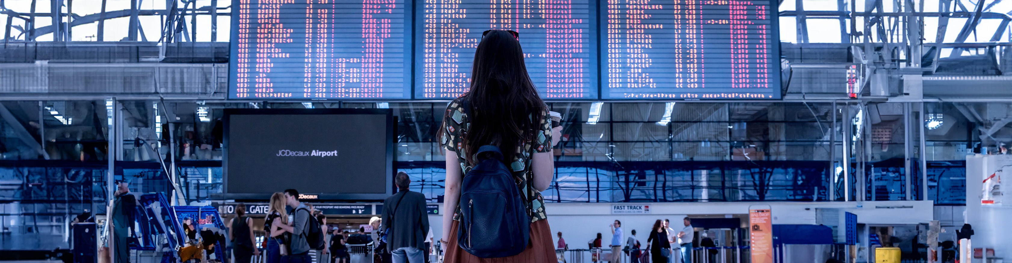 girl looking at airport terminal arrivals board