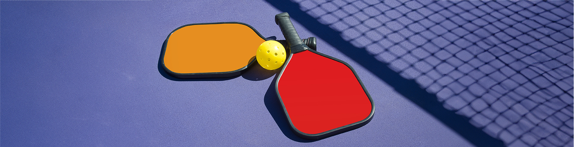 pickleball paddles near the shadow of netting