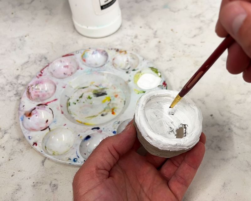 Fully dry coil pot being painted with acrylic white paint. 