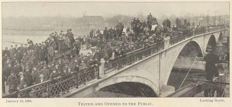 A sepia toned image of a large crowd standing on the newly opened Melan Bridge; caption reads January 12, 1898, Tested and Opened to the Public, Looking North