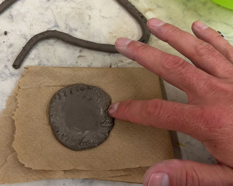 Applying water to scored section of base lay of coil pot.
