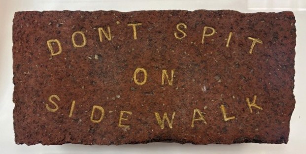 Color photograph of a red brick stamped in gold 