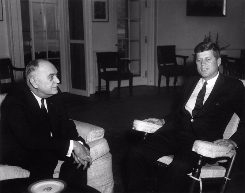 Black and white photograph showing Dr. William Menninger, left, seated in the Oval Office with President John F. Kennedy (right)