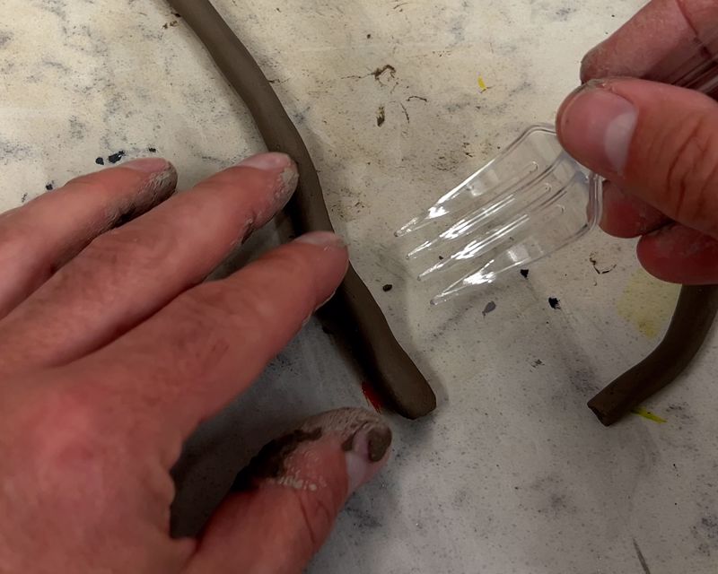 Using a plastic fork to score one side of the coil.