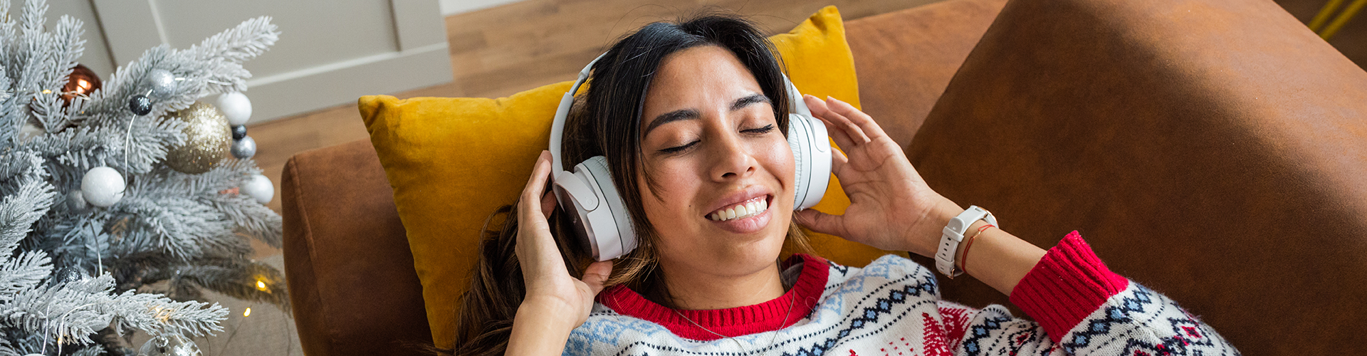 woman listening to music by a Christmas tree