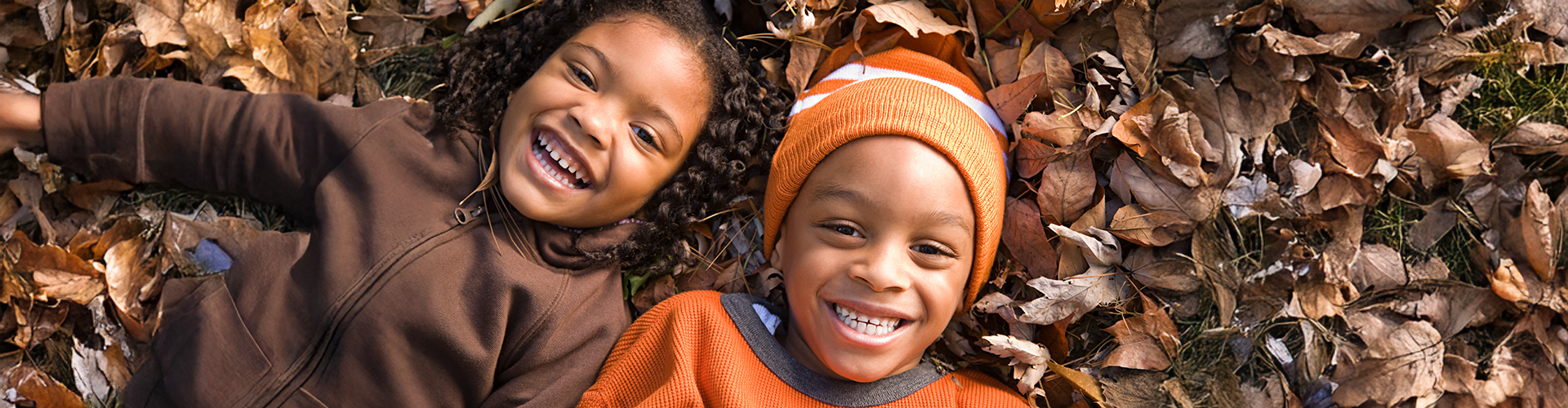 girl and boy smiling in leaves