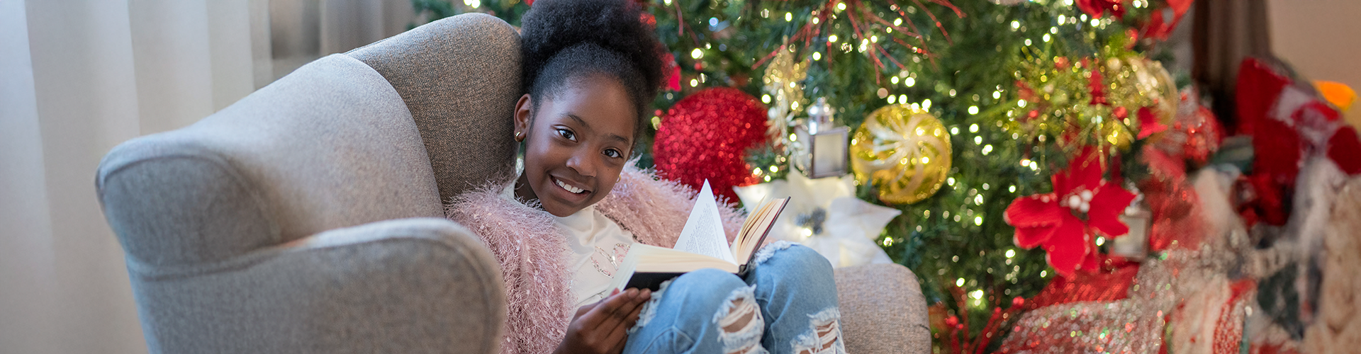 girl reading by Christmas tree