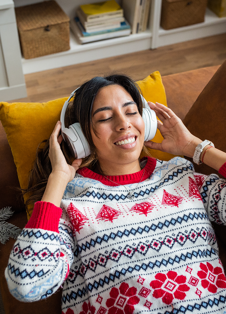 woman in a holiday sweater listening to headphones