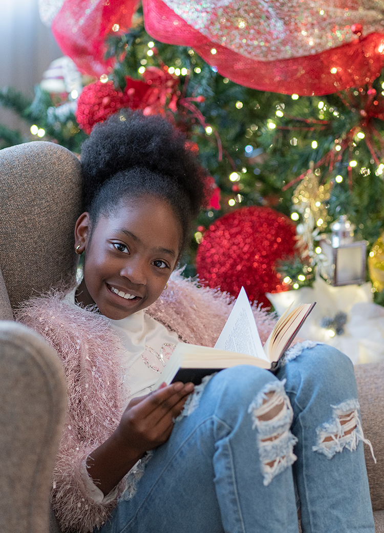 girl reading by Christmas tree