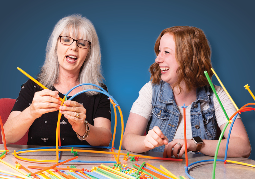 2 ladies building with colorful straws