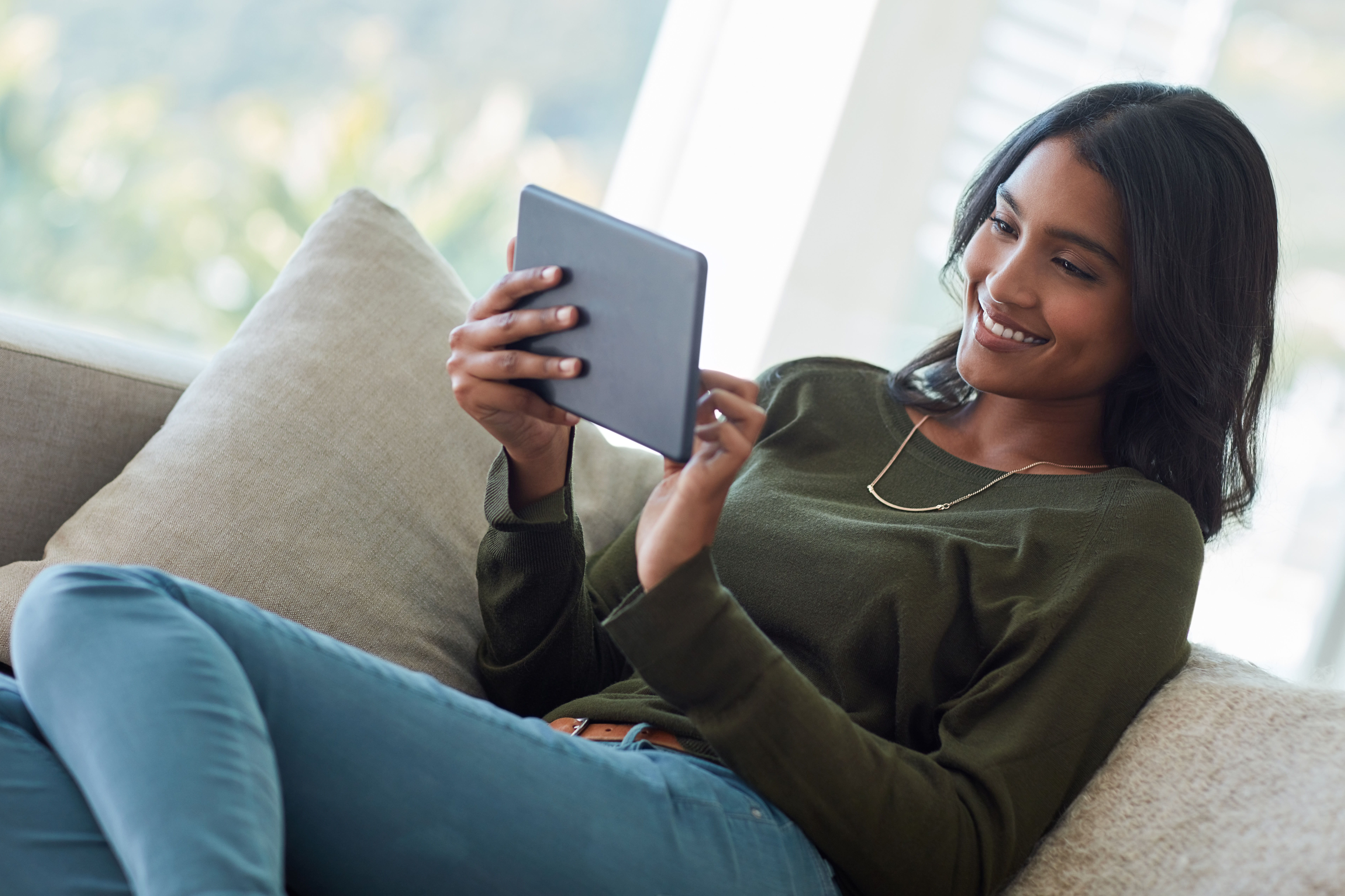 young woman using her tablet while sitting on the sofa at home