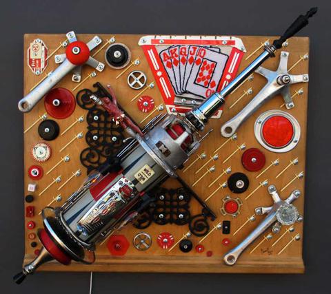 Sculpture of rocket using hardware and machine parts along with black, red and white plastic and graphic elements.