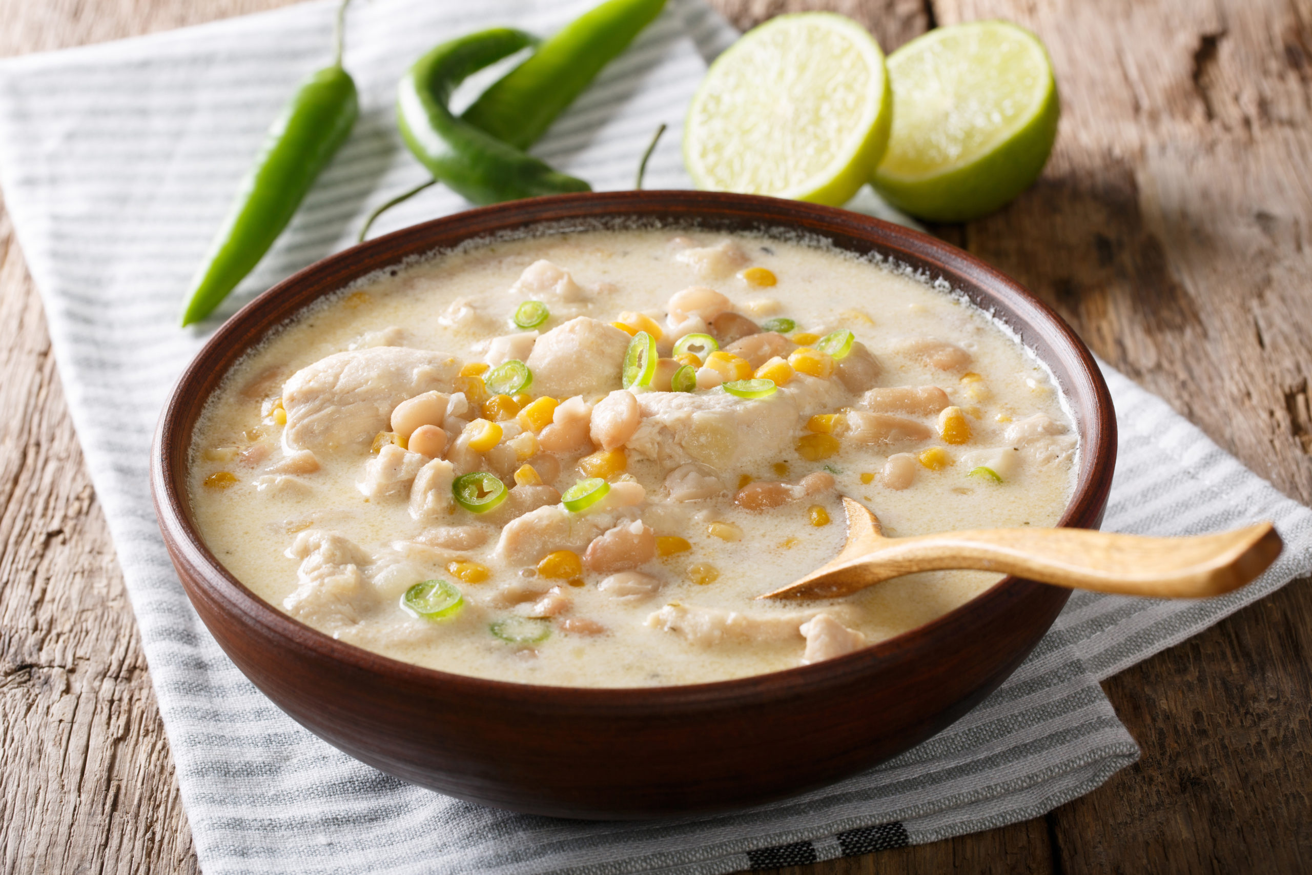 Homemade white chili chicken with beans, lime and corn close-up on the table