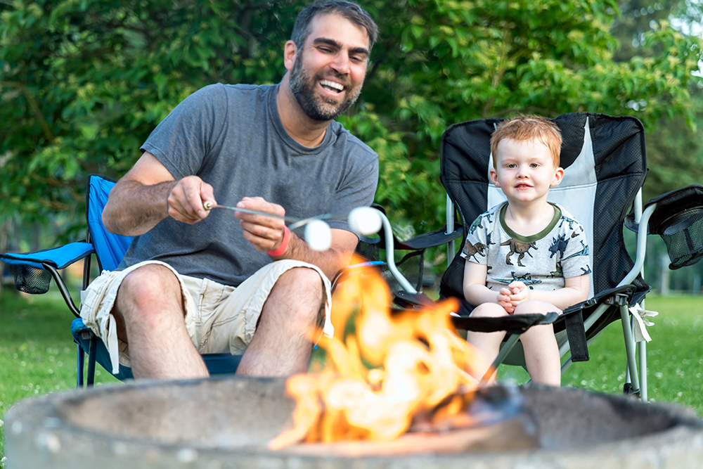 Father and Son Roasting Marshmallow over Campfire in Camping in Summer