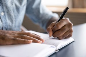 Man sits at a desk and writes in a journal Man sits at a desk and writes in a journal