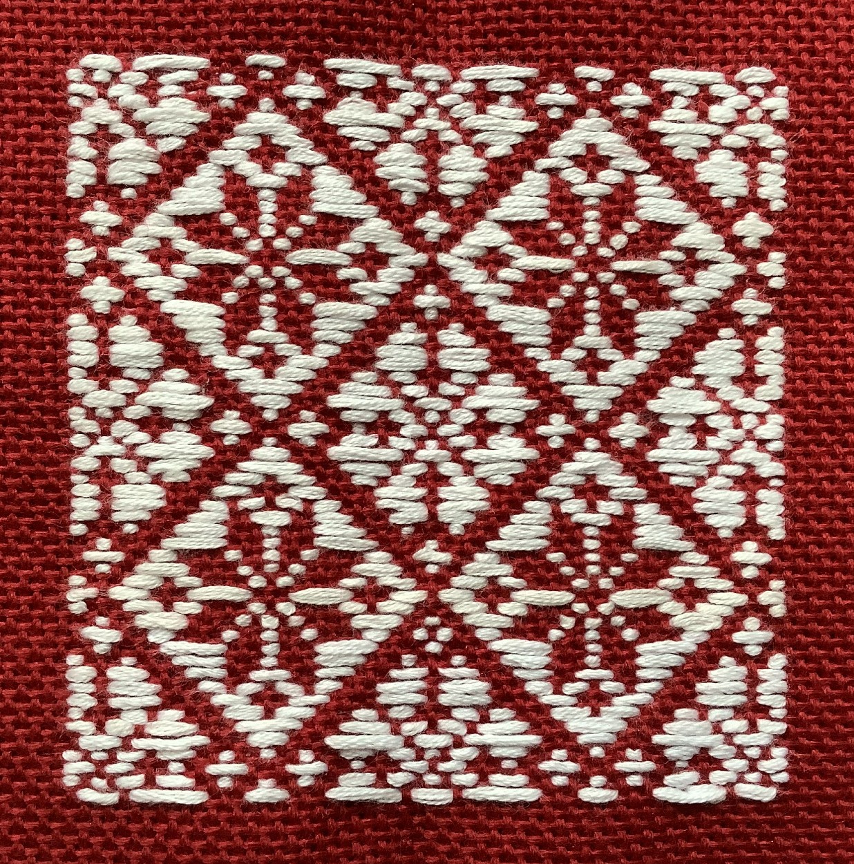 white stitching in geometric pattern on red cloth