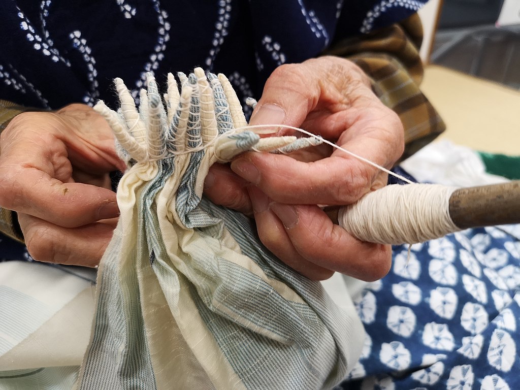 hands holding fabric with thread wrapped around it