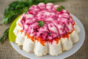 Traditional herring under boiled vegetables in gelatin on a plate