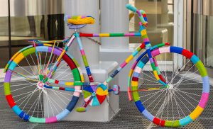 Rainbow bike decorated with colored threads, transport decorated in the hippie boho style. Beautiful bicycles no people. Decorated bike standing next to the column of the shopping center