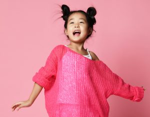 girl in pink sweater sings happy smiling