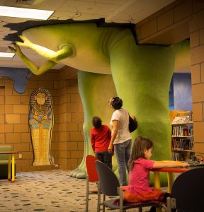 kid and adult looking at dinosaur legs in Kids Library